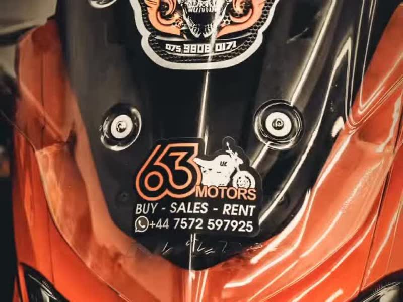 Close-up of a customer's orange motorbike with a 63 Motors sticker on the headlight cowl
